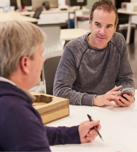 Two men discussing a prototype at a table in the office