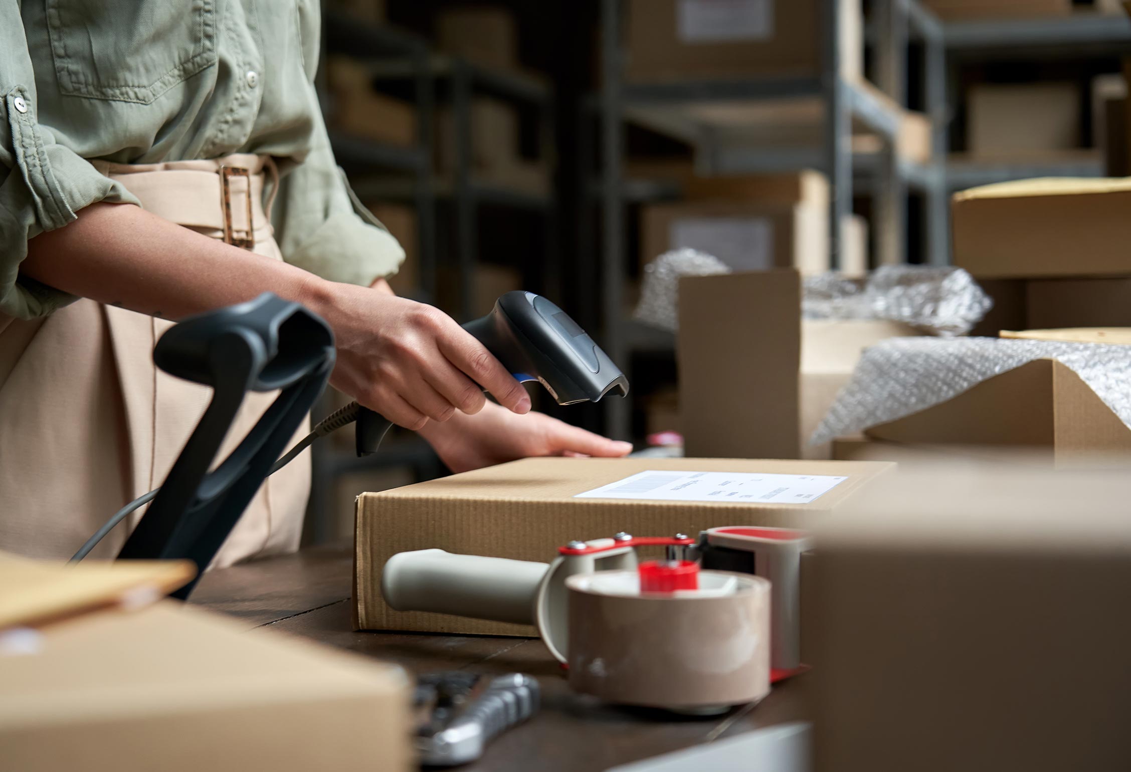 Hand holding a barcode scanner over a packing box